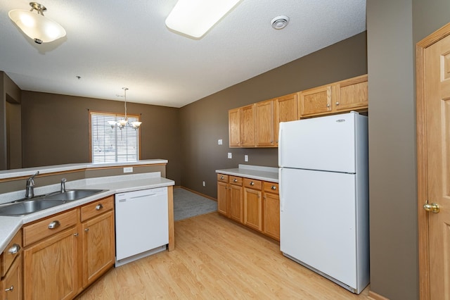 kitchen with white appliances, a sink, hanging light fixtures, light countertops, and light wood-style floors