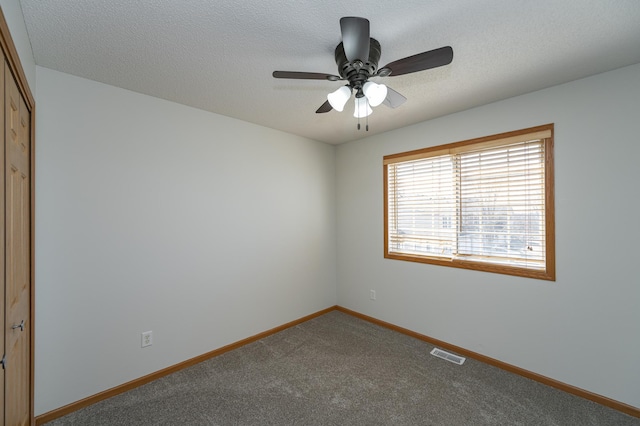 carpeted spare room featuring visible vents, a textured ceiling, baseboards, and a ceiling fan