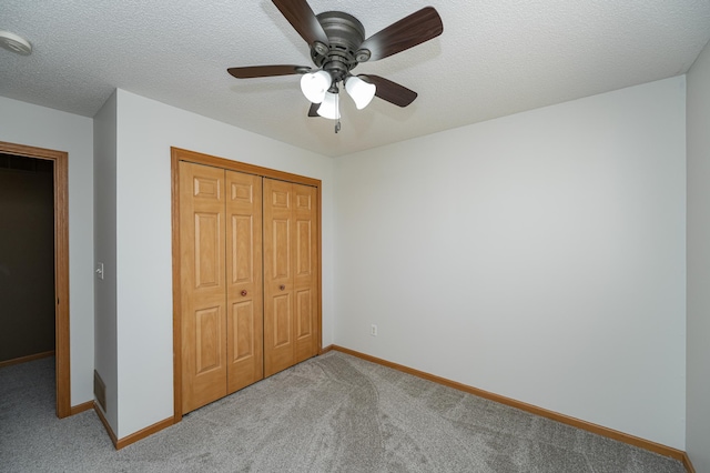 unfurnished bedroom with a ceiling fan, a textured ceiling, a closet, carpet flooring, and baseboards