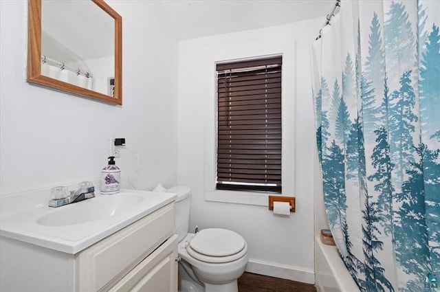 bathroom featuring vanity, wood finished floors, baseboards, shower / bath combo with shower curtain, and toilet