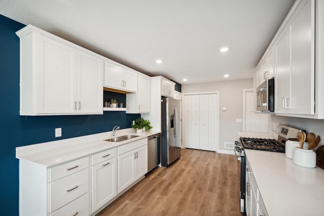 kitchen with white cabinets, appliances with stainless steel finishes, open shelves, and a sink