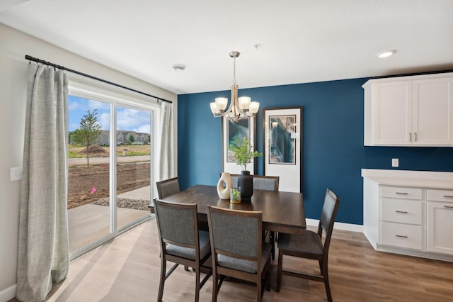 dining space featuring light wood-style flooring, a notable chandelier, and baseboards