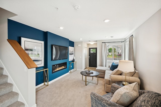 living room featuring baseboards, stairs, carpet floors, recessed lighting, and a glass covered fireplace