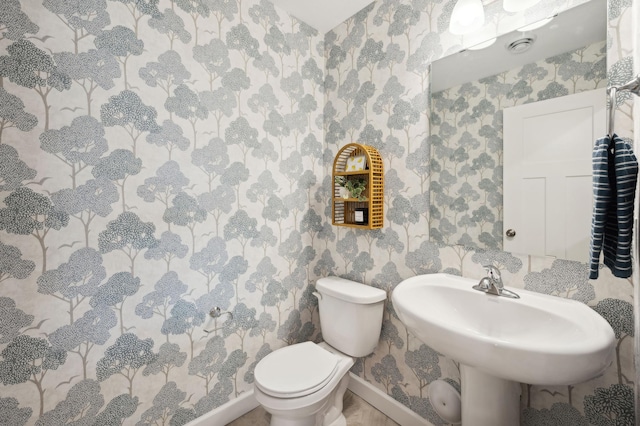 bathroom with baseboards, toilet, and wallpapered walls