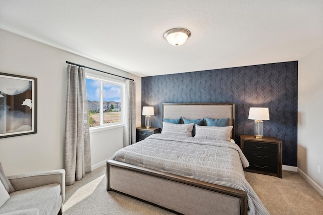 bedroom with wallpapered walls, an accent wall, baseboards, and carpet