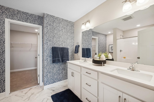 bathroom with a sink, visible vents, walk in shower, and wallpapered walls