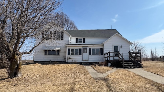 traditional-style home featuring a wooden deck and roof with shingles