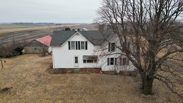 view of front of property with a rural view and roof with shingles