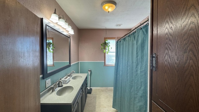 full bathroom with double vanity, visible vents, wainscoting, and a sink