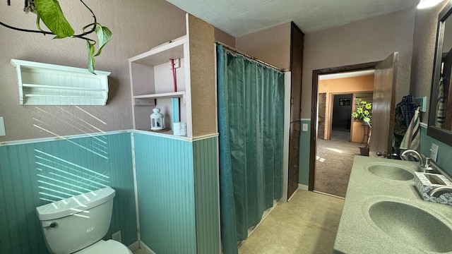 full bathroom featuring a shower with shower curtain, double vanity, toilet, and a sink