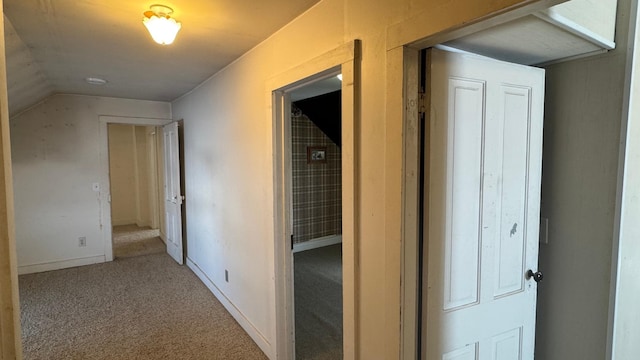 hall featuring vaulted ceiling, carpet flooring, and baseboards