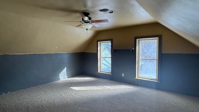 bonus room with a textured ceiling, vaulted ceiling, a ceiling fan, and carpet