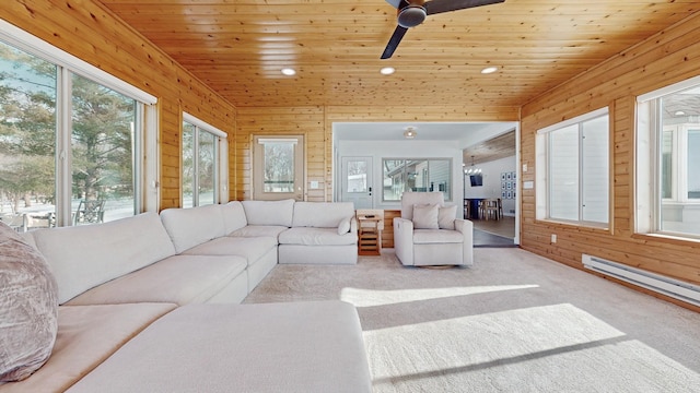 carpeted living area with wood walls, wooden ceiling, a healthy amount of sunlight, and a ceiling fan