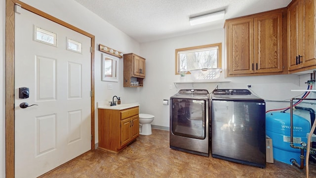 washroom featuring baseboards, laundry area, separate washer and dryer, a sink, and a textured ceiling