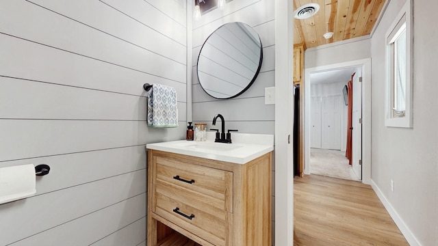 bathroom with visible vents, vanity, baseboards, and wood finished floors