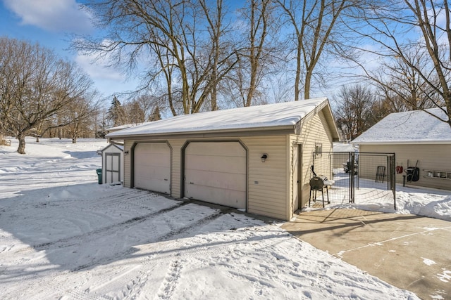 snow covered garage featuring a detached garage and a gate