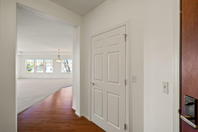 hallway with baseboards, dark wood finished floors, and an inviting chandelier