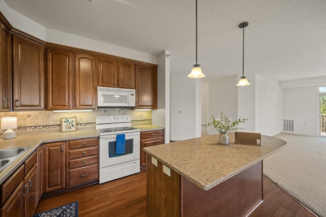 kitchen featuring visible vents, decorative backsplash, white appliances, a center island, and a textured ceiling