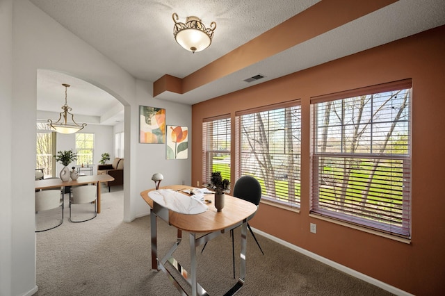 carpeted home office featuring visible vents, arched walkways, baseboards, and a textured ceiling
