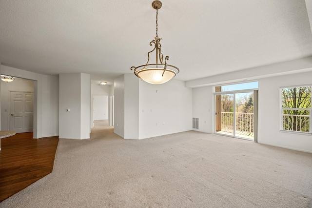 unfurnished living room featuring visible vents, a textured ceiling, and light colored carpet