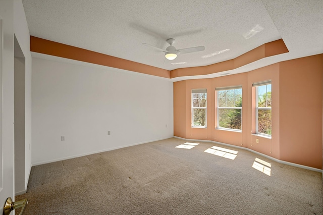 carpeted spare room with baseboards, ceiling fan, and a textured ceiling