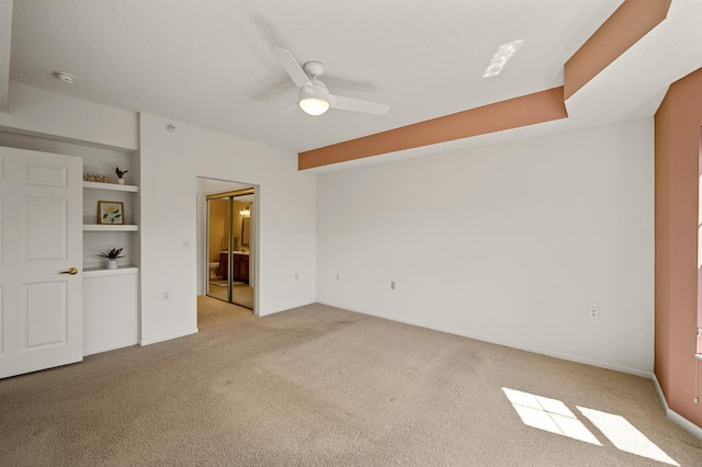 unfurnished bedroom with ensuite bathroom, light carpet, and ceiling fan