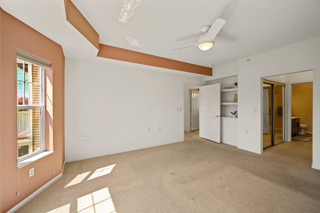 unfurnished bedroom featuring ensuite bathroom, a ceiling fan, baseboards, and light carpet