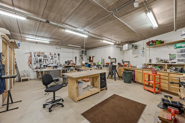 miscellaneous room with concrete block wall, a workshop area, and concrete flooring
