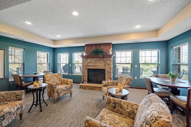 carpeted living area with plenty of natural light, a fireplace, and a textured ceiling