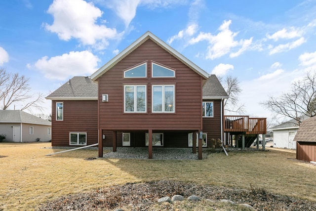 rear view of property featuring a yard, roof with shingles, and a deck