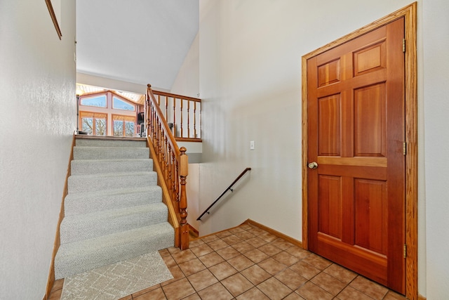 staircase featuring tile patterned floors, baseboards, and vaulted ceiling