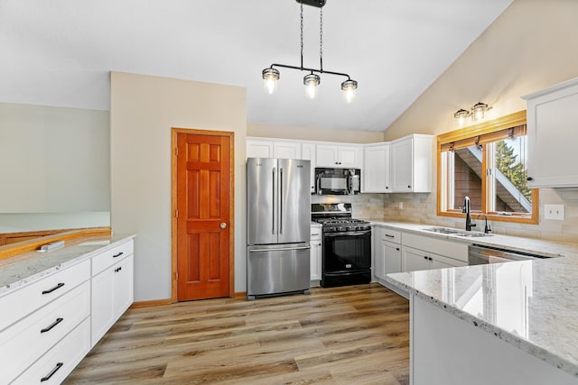 kitchen with a sink, light wood-type flooring, black appliances, and vaulted ceiling