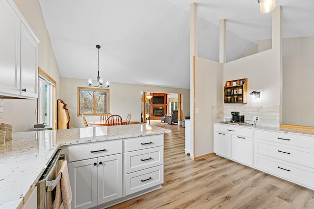 kitchen with a peninsula, white cabinets, light wood-style floors, and lofted ceiling