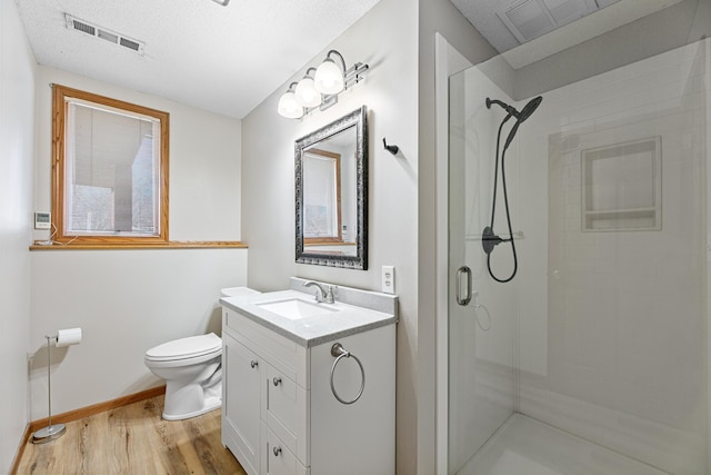 bathroom featuring visible vents, a shower stall, toilet, and wood finished floors