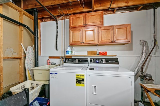 laundry room featuring washing machine and clothes dryer, cabinet space, and a sink