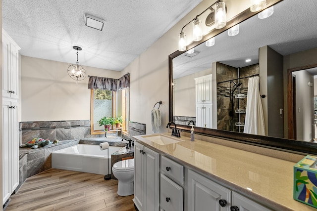 full bathroom featuring a garden tub, a textured ceiling, wood finished floors, tiled shower, and vanity