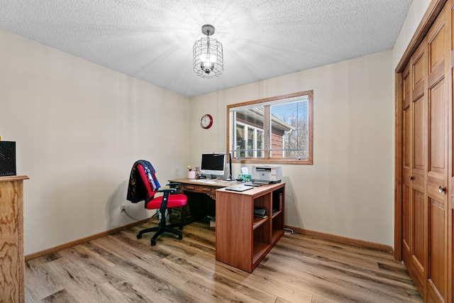 office area with a textured ceiling, baseboards, light wood finished floors, and a chandelier