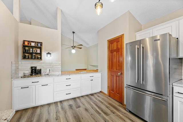 kitchen featuring light stone countertops, ceiling fan, vaulted ceiling, white cabinets, and high quality fridge