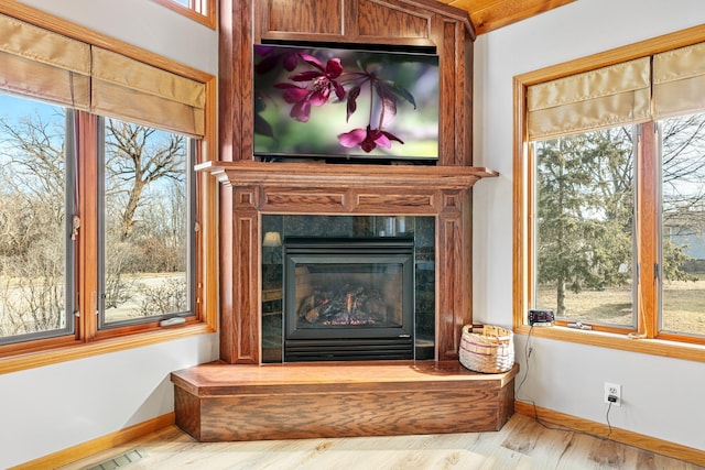 interior details featuring a tiled fireplace, visible vents, baseboards, and wood finished floors