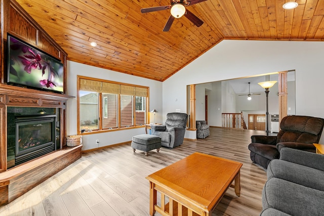 living area featuring a ceiling fan, lofted ceiling, wood ceiling, a glass covered fireplace, and light wood-type flooring