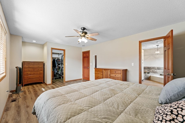 bedroom featuring ensuite bathroom, a textured ceiling, wood finished floors, a closet, and a spacious closet