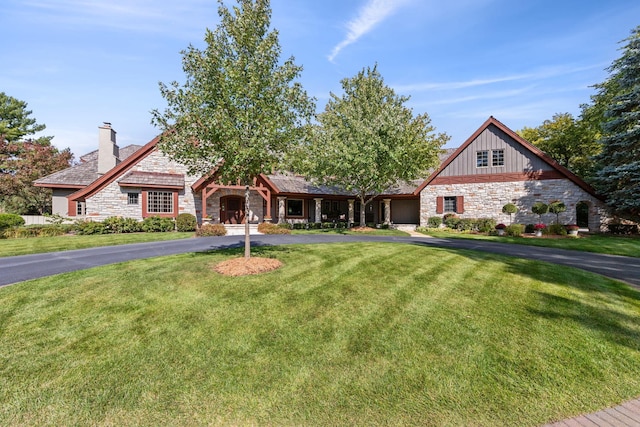 view of front of property featuring stone siding, board and batten siding, a chimney, and a front yard