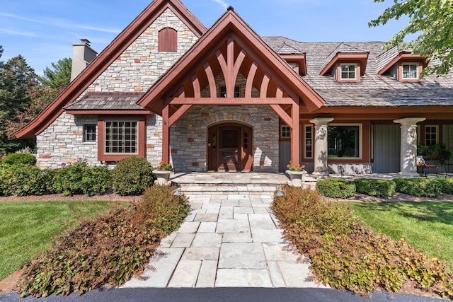 view of front facade with a front yard, stone siding, and a chimney