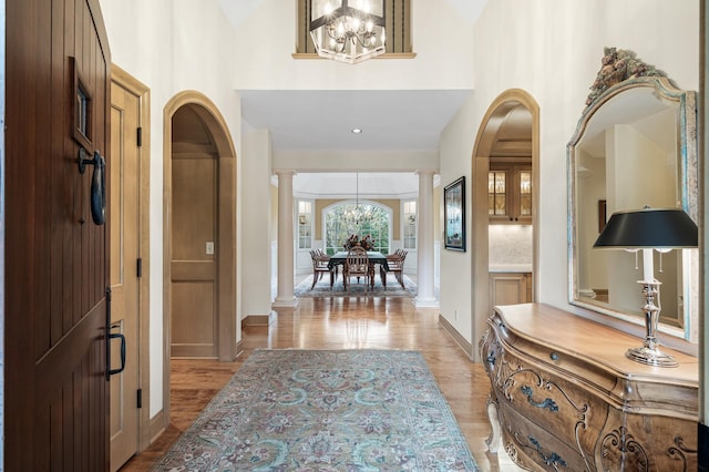 781 Ferndale Rd N, Orono, MN 55391 - entryway featuring ornate columns, an inviting chandelier, light wood-style flooring, a high ceiling, and baseboards