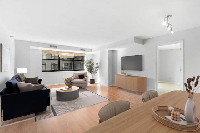 living room featuring visible vents, baseboards, and light wood-style floors