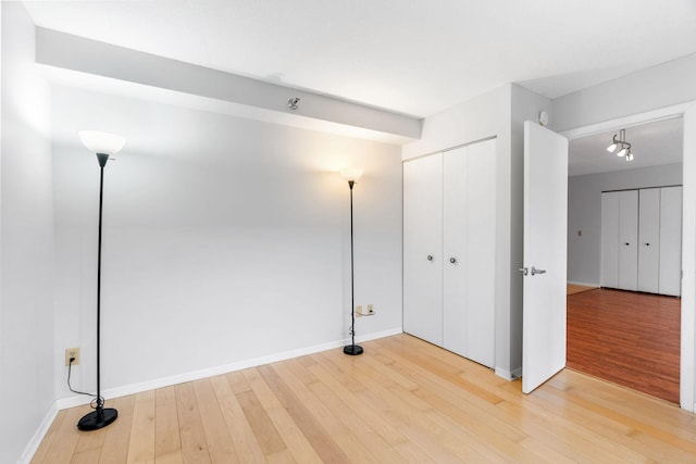 unfurnished bedroom featuring baseboards, light wood-type flooring, and a closet