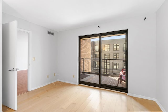 unfurnished room with light wood-type flooring, visible vents, and baseboards