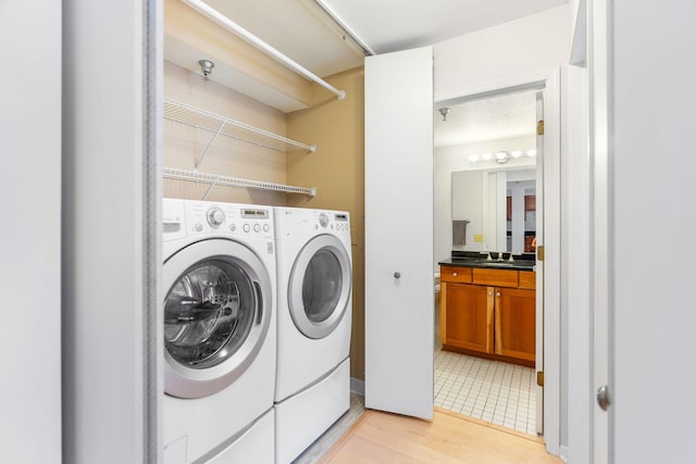 laundry room featuring laundry area, washing machine and dryer, and light wood-style flooring