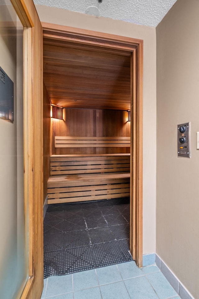 relaxing sauna / steam room featuring tile patterned flooring and baseboards