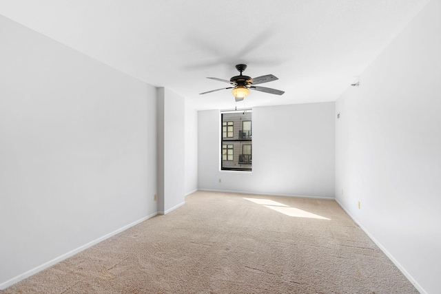 carpeted empty room with a ceiling fan and baseboards